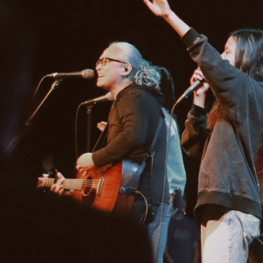 older woman singing on worship stage