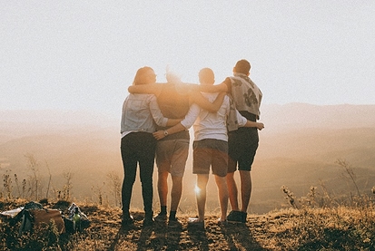 Silhouette of four friends hugging at sunset