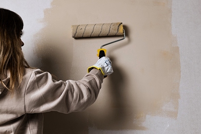 Woman painting wall beige
