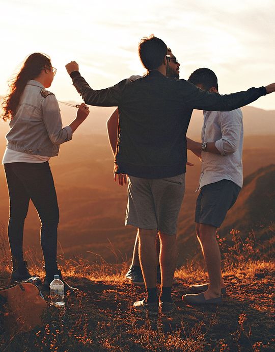 young adults having fun overlooking mountain at sunset