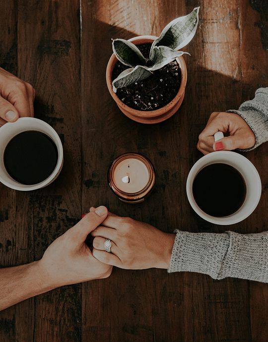 couple holding hands with coffees
