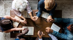 group of christians praying together at bible study