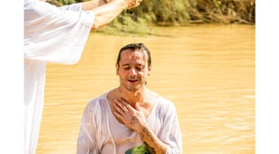 man getting baptized in lake