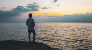 man on beach watching sunrise feeling God's glory