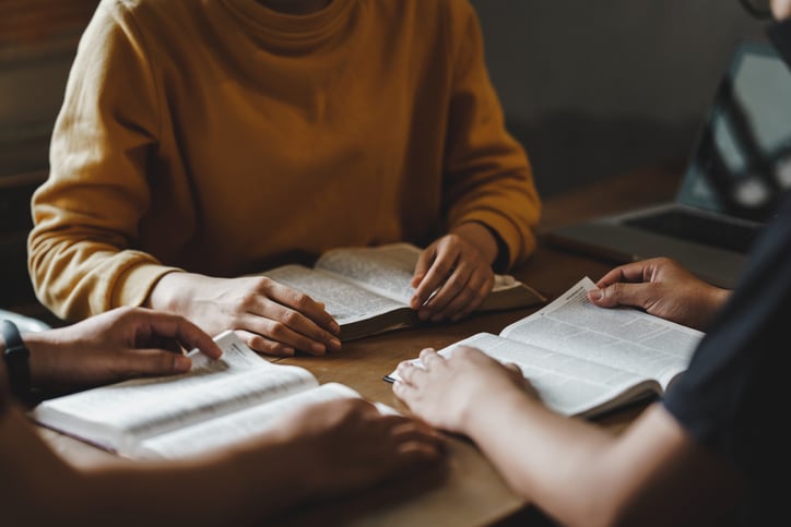 People studying the Bible together on a wooden table indoors