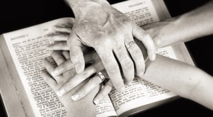 a couple's hands on the bible as they read together