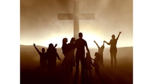 silhouetted people in front of cross with mist