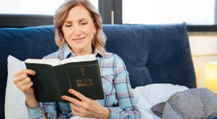 woman reading bible in bed
