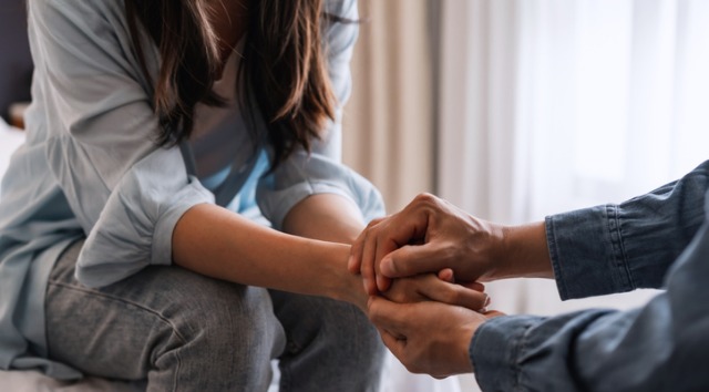 close up of young couple holding hands while seated across from each other